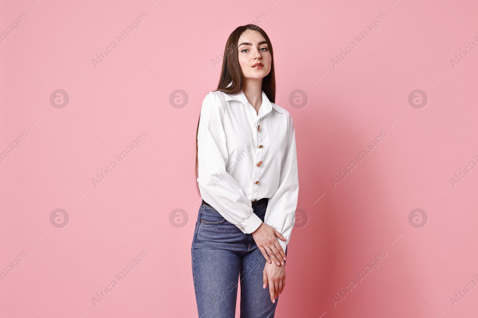 Photo of Beautiful young woman in stylish jeans on pink background