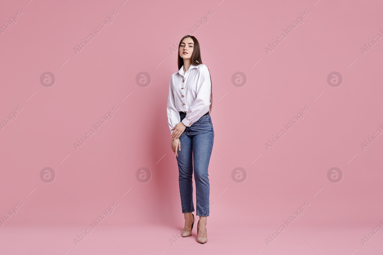 Photo of Beautiful young woman in stylish jeans on pink background