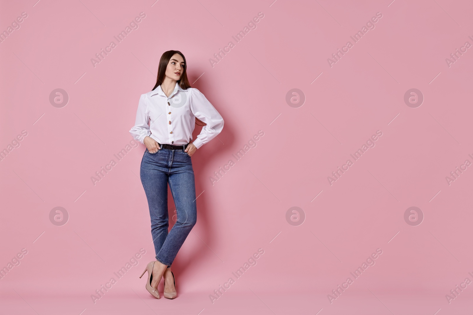 Photo of Woman in stylish jeans on pink background. Space for text