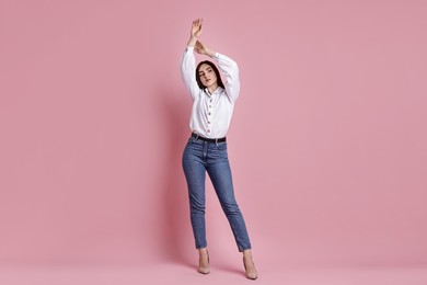 Photo of Beautiful young woman in stylish jeans on pink background