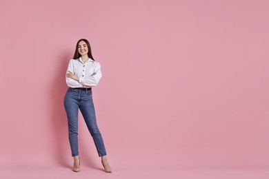 Photo of Happy woman in stylish jeans on pink background. Space for text