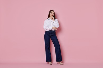 Photo of Beautiful young woman in stylish jeans on pink background