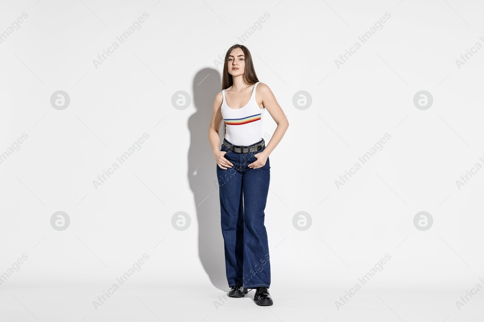 Photo of Beautiful young woman in stylish jeans on light background