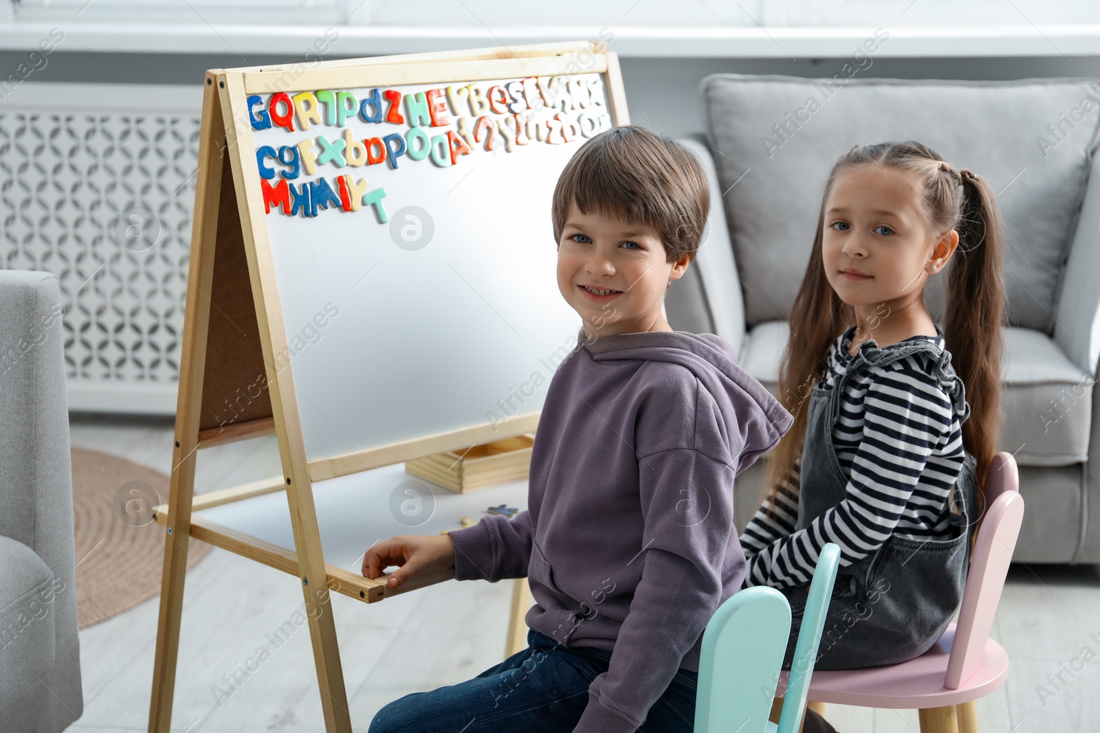 Photo of Little kids learning alphabet with magnetic letters indoors