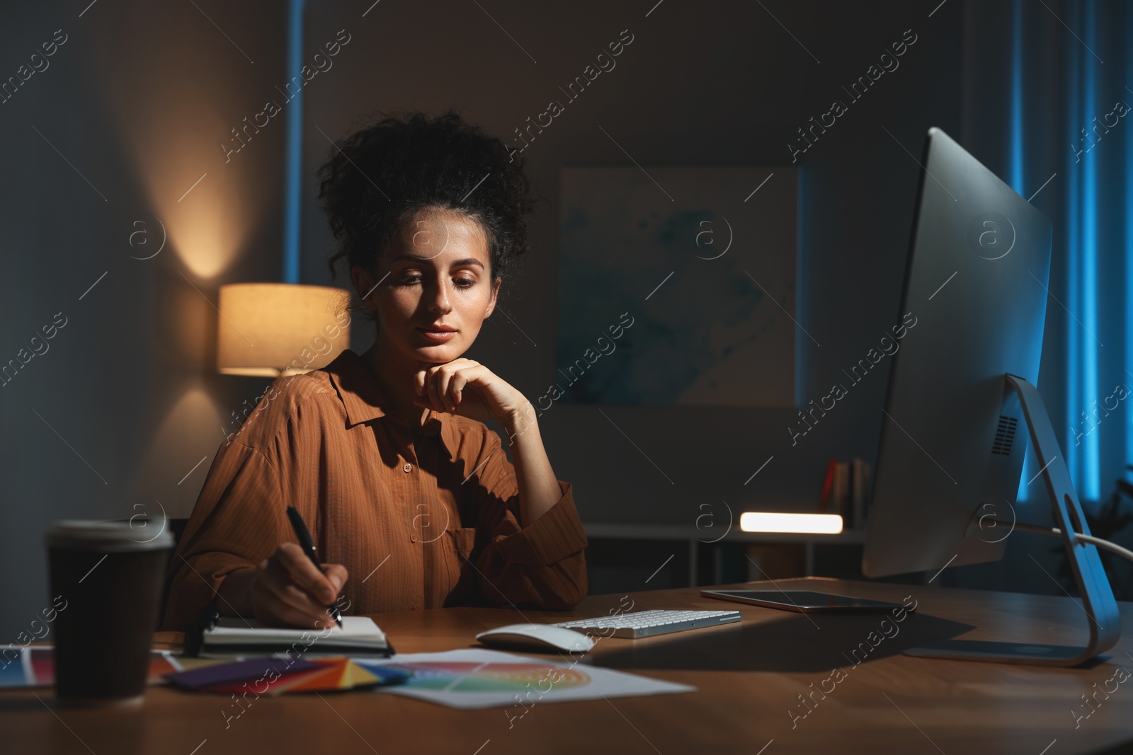 Photo of Designer with notebook working indoors at night