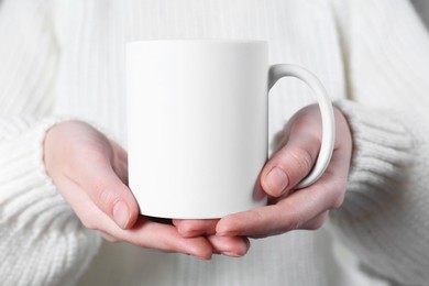 Photo of Woman holding blank white ceramic mug, closeup. Mockup for design