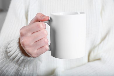 Photo of Woman holding blank white ceramic mug, closeup. Mockup for design