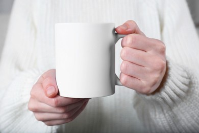 Photo of Woman holding blank white ceramic mug, closeup. Mockup for design