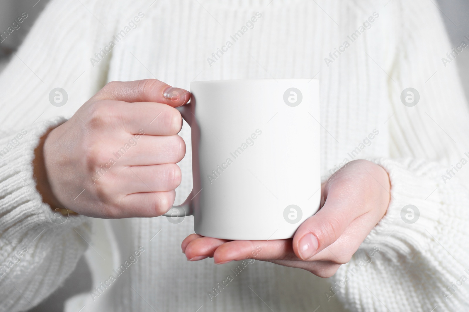 Photo of Woman holding blank white ceramic mug, closeup. Mockup for design