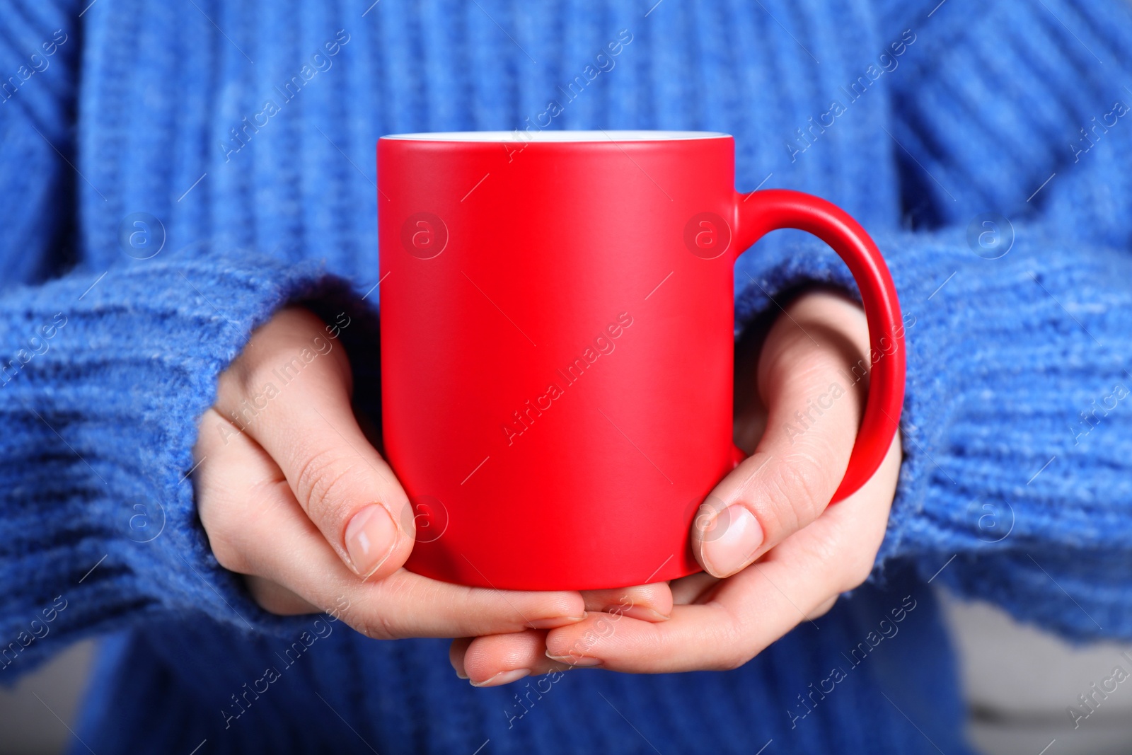 Photo of Woman holding blank red ceramic mug, closeup. Mockup for design