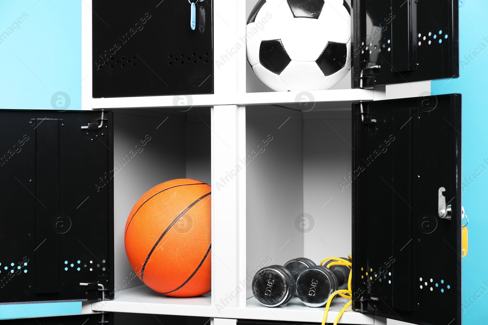 Photo of Open lockers with sport equipment on light blue background