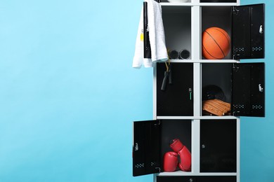 Photo of Open lockers with sport equipment on light blue background, space for text