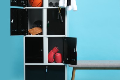 Open lockers with sport equipment and bench on light blue background