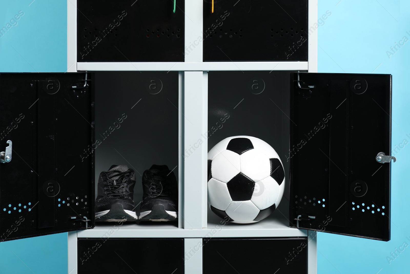 Photo of Open lockers with soccer ball and sneakers on light blue background