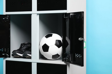 Photo of Open lockers with soccer ball and sneakers on light blue background