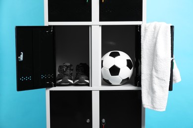 Photo of Open lockers with soccer ball, sneakers and towel on light blue background