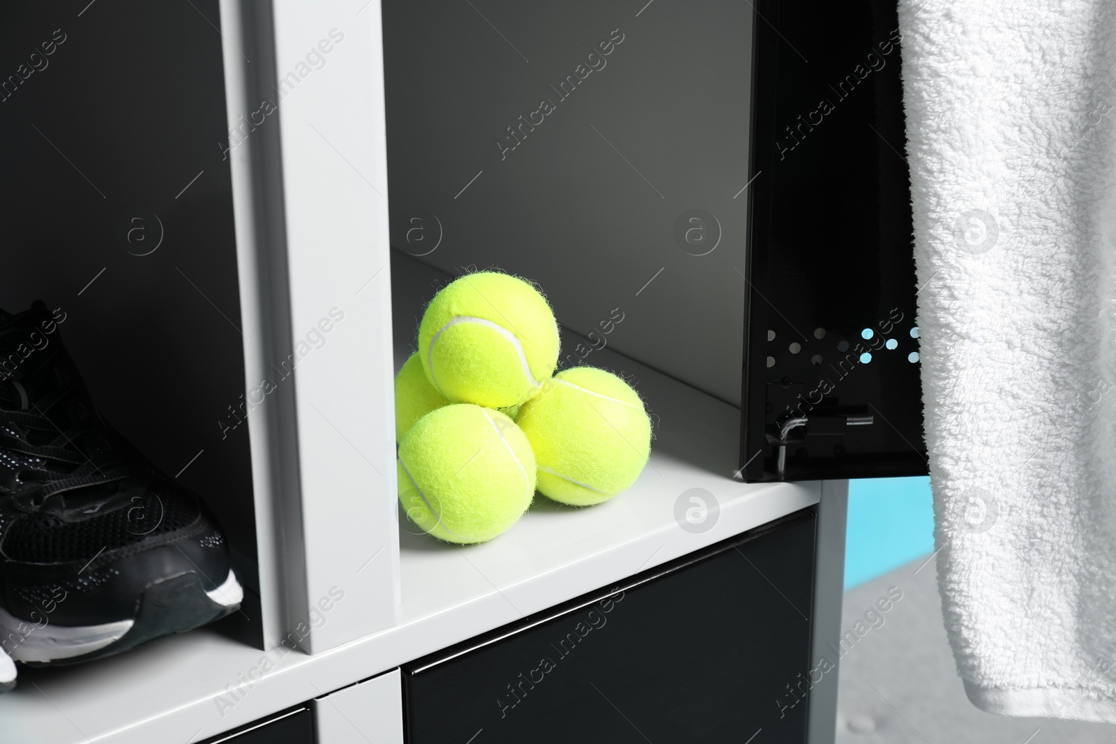 Photo of Open lockers with tennis balls, sneaker and towel, closeup