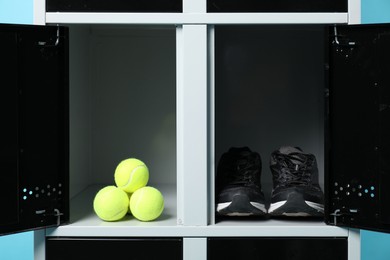 Photo of Open locker with sneakers and tennis balls on light blue background