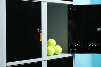 Photo of Open locker with tennis balls on light blue background