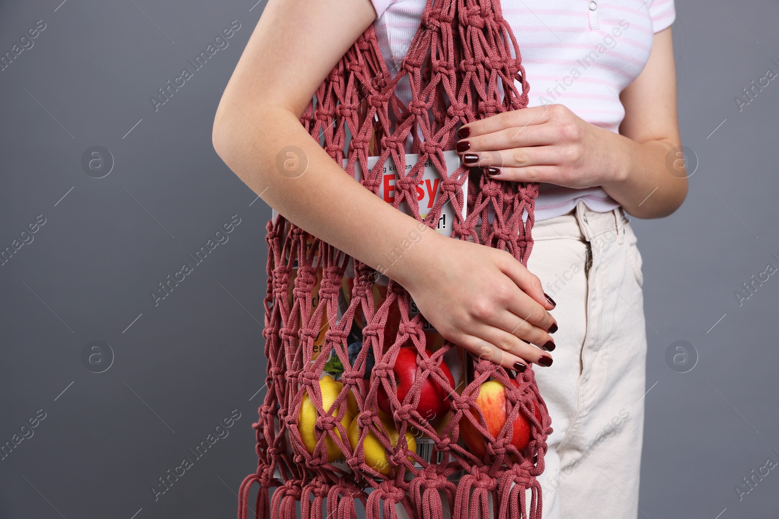 Photo of Teenage girl with handmade macrame bag on grey background, closeup