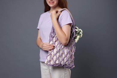 Teenage girl with handmade macrame bag on grey background, closeup