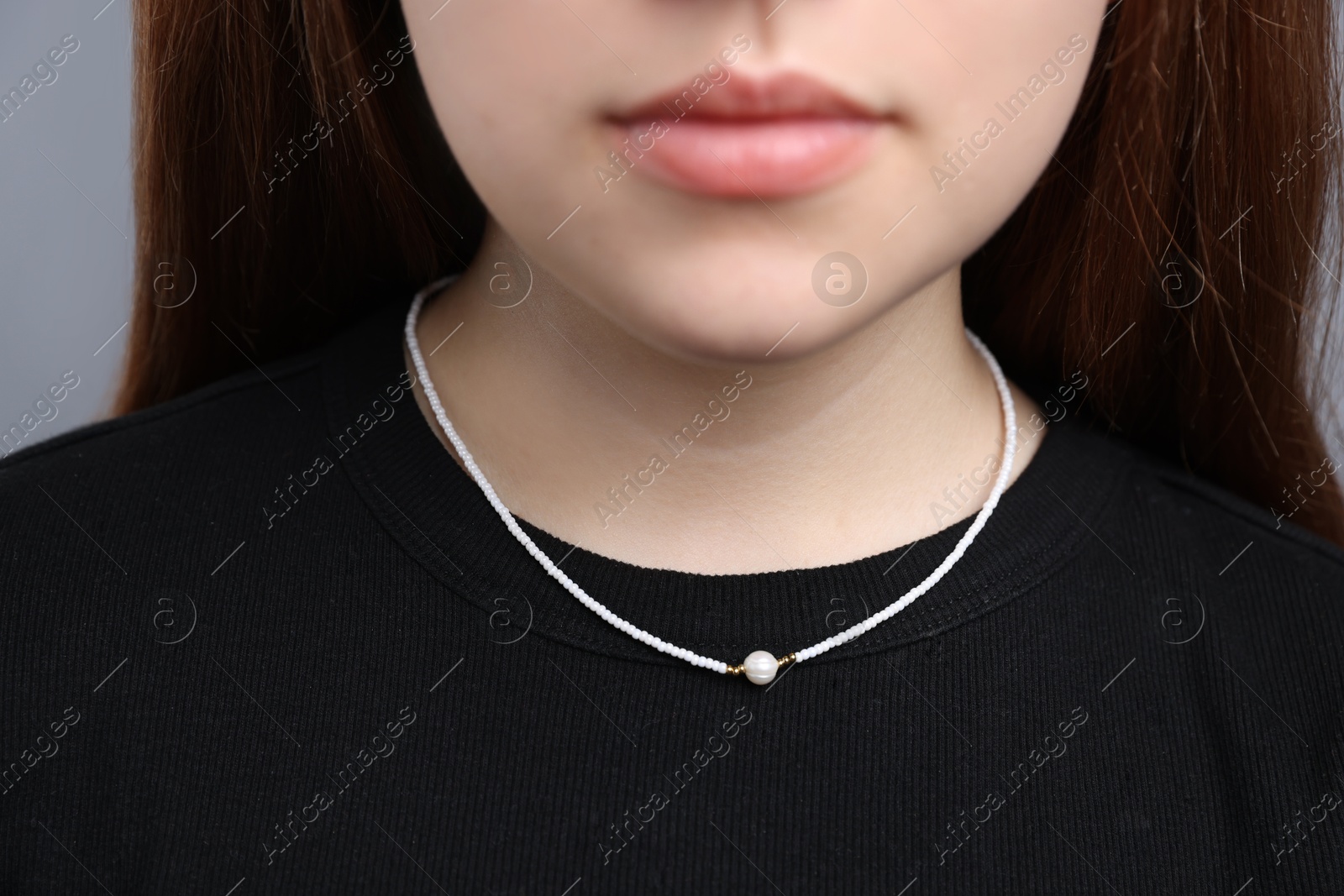 Photo of Teenage girl wearing stylish necklace on grey background, closeup