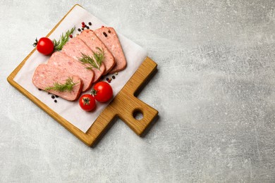 Photo of Pieces of tasty canned meat, dill, peppercorns and tomatoes on grey textured table, top view. Space for text