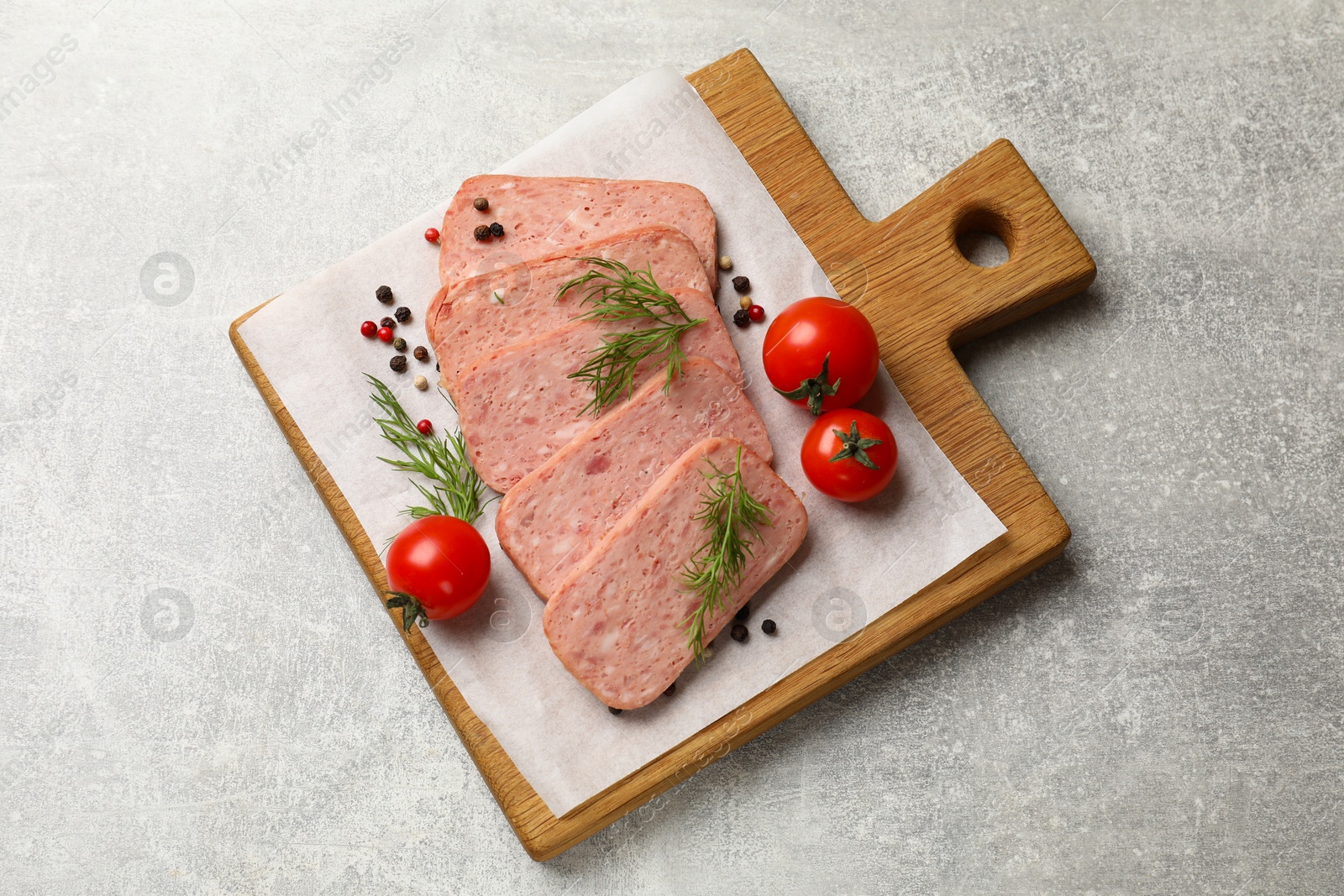 Photo of Pieces of tasty canned meat, dill, peppercorns and tomatoes on grey textured table, top view