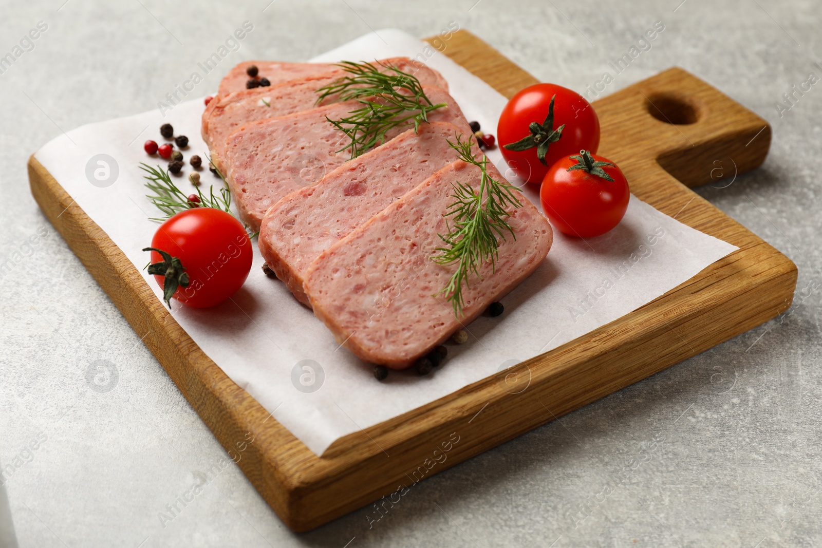 Photo of Pieces of tasty canned meat, dill, peppercorns and tomatoes on grey textured table, closeup