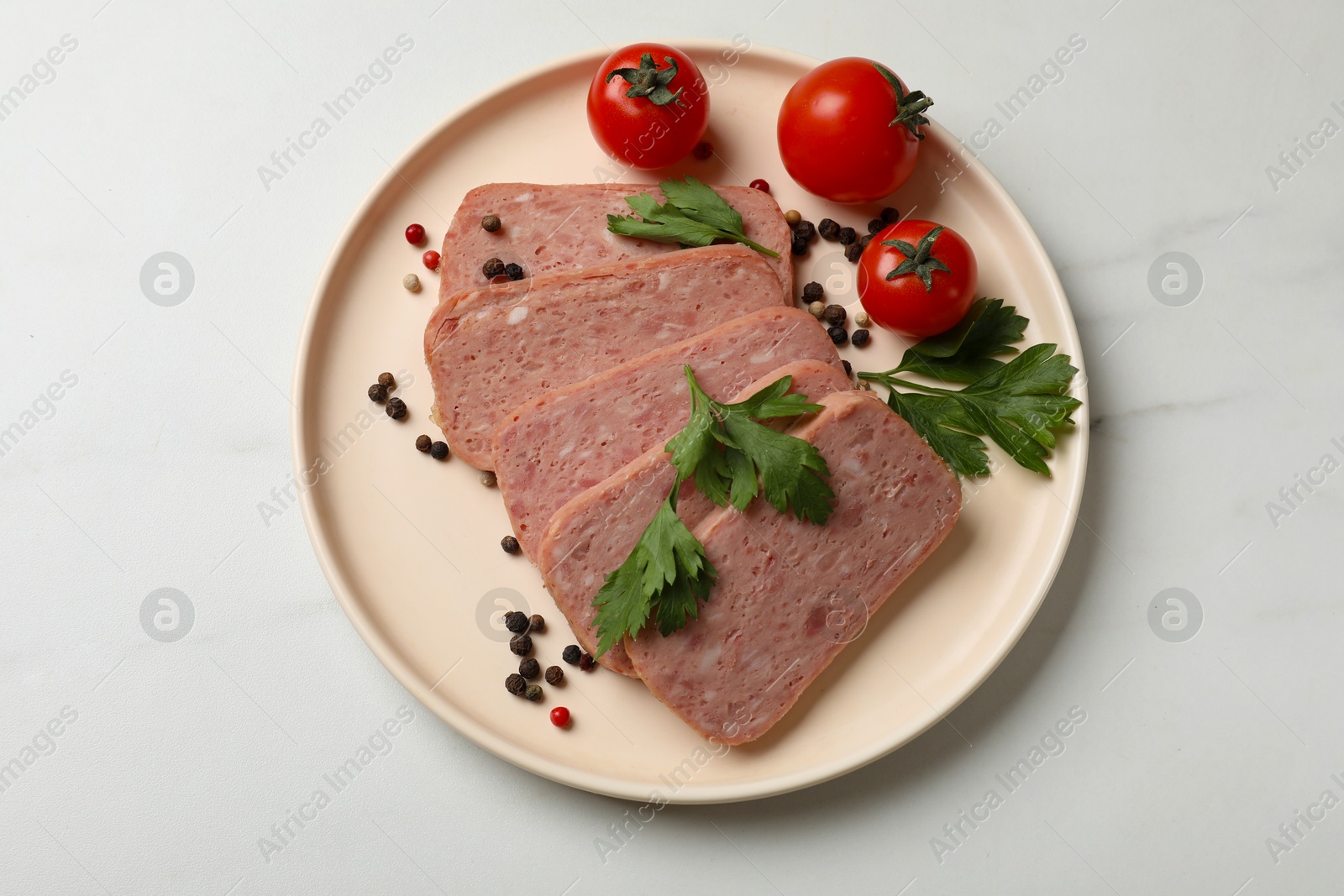 Photo of Pieces of tasty canned meat, parsley, peppercorns and tomatoes on white marble table, top view