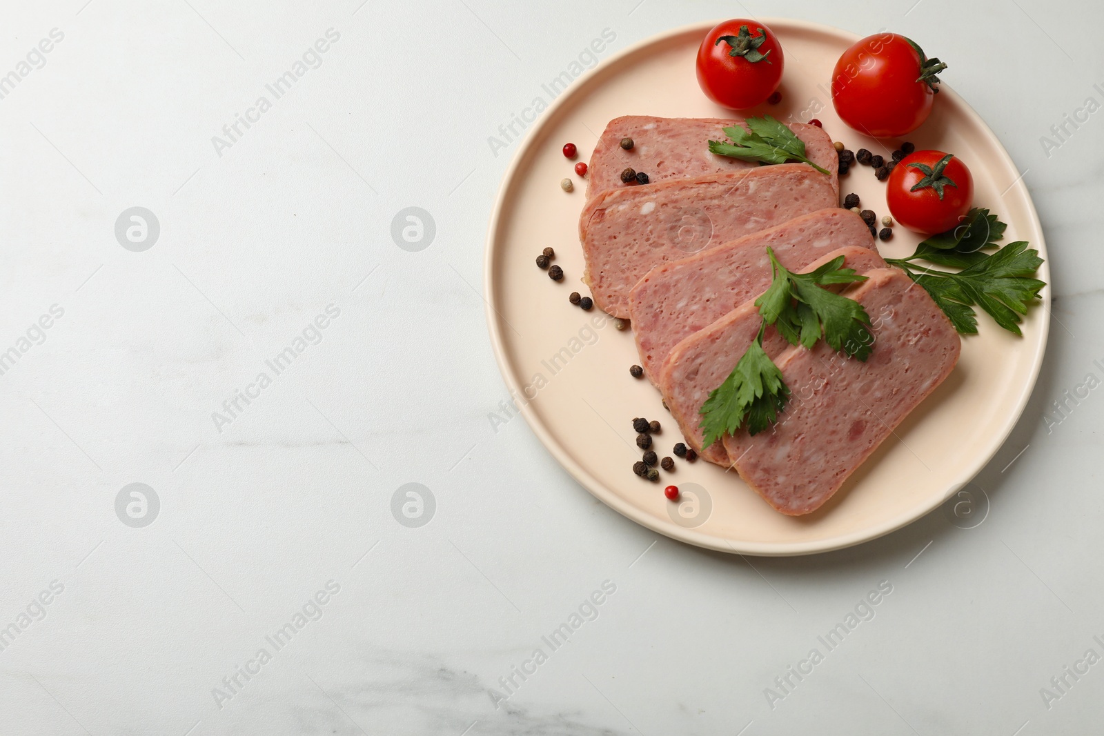 Photo of Pieces of tasty canned meat, parsley, peppercorns and tomatoes on white marble table, top view. Space for text