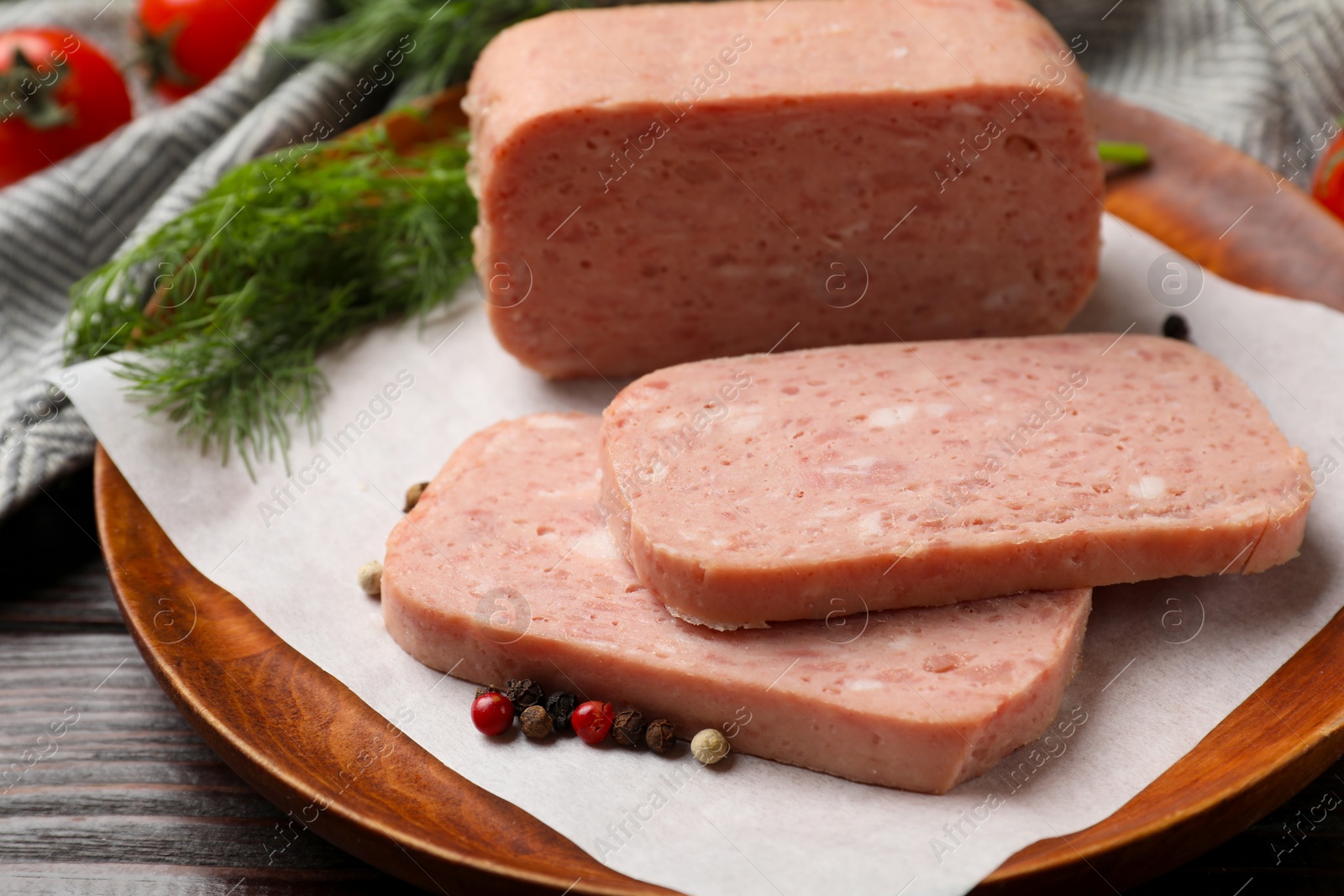 Photo of Pieces of tasty canned meat and peppercorns on wooden table, closeup