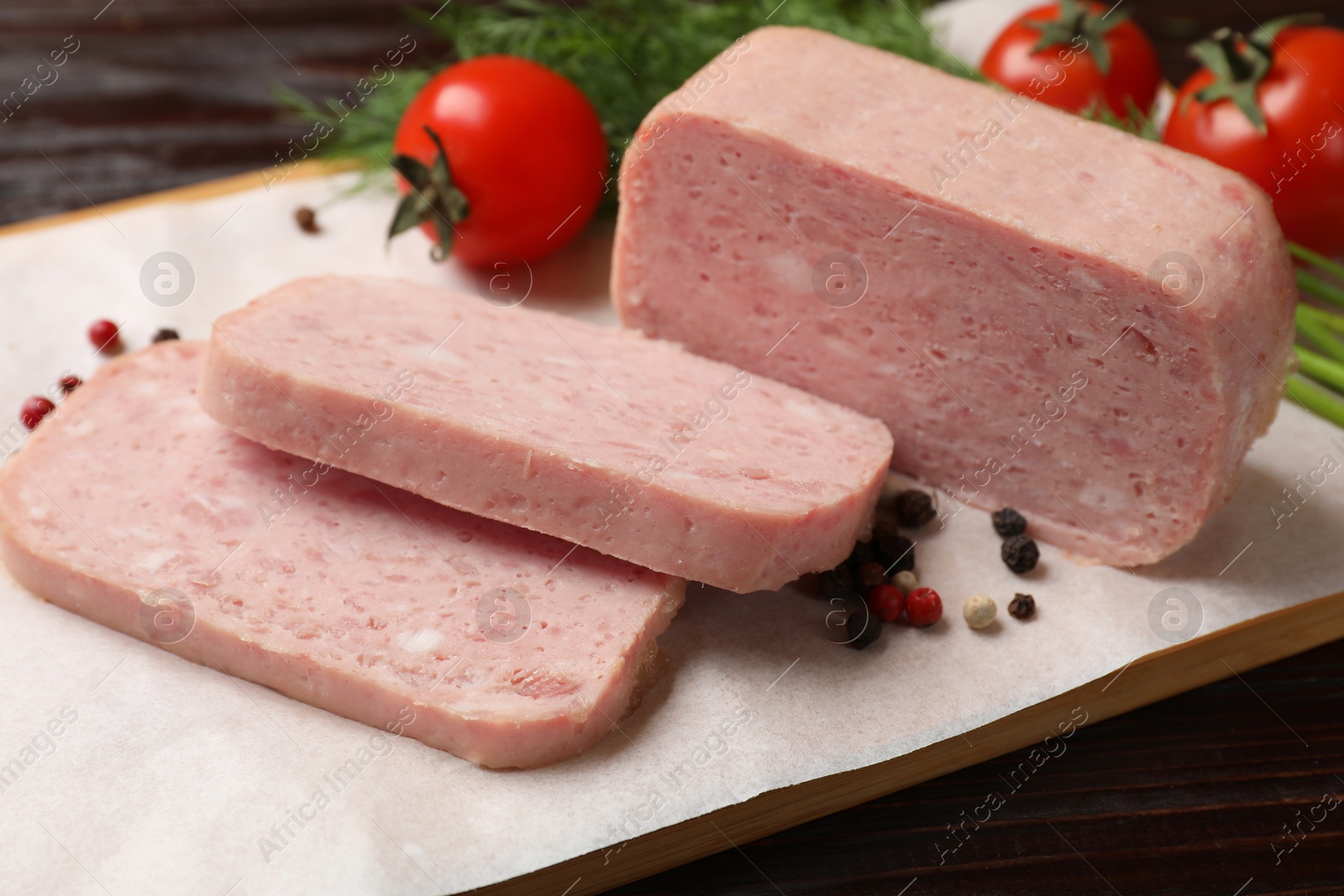 Photo of Pieces of tasty canned meat and peppercorns on wooden table, closeup