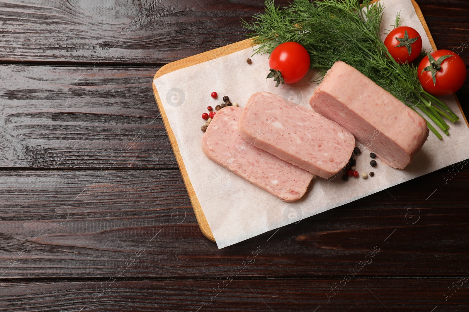 Photo of Pieces of tasty canned meat, tomatoes, dill and peppercorns on wooden table, top view. Space for text