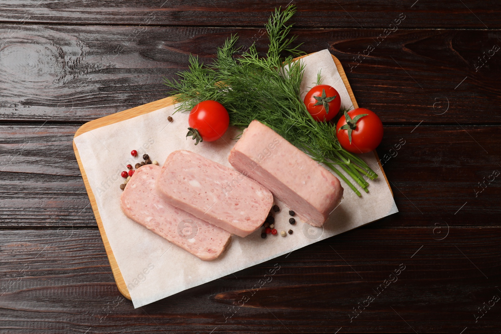 Photo of Pieces of tasty canned meat, tomatoes, dill and peppercorns on wooden table, top view