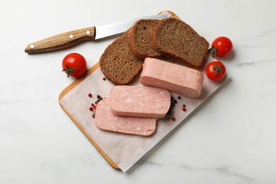 Photo of Pieces of tasty canned meat, tomatoes, peppercorns and bread on white marble table, flat lay