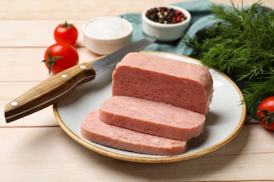 Photo of Pieces of tasty canned meat, dill and tomatoes on light wooden table, closeup