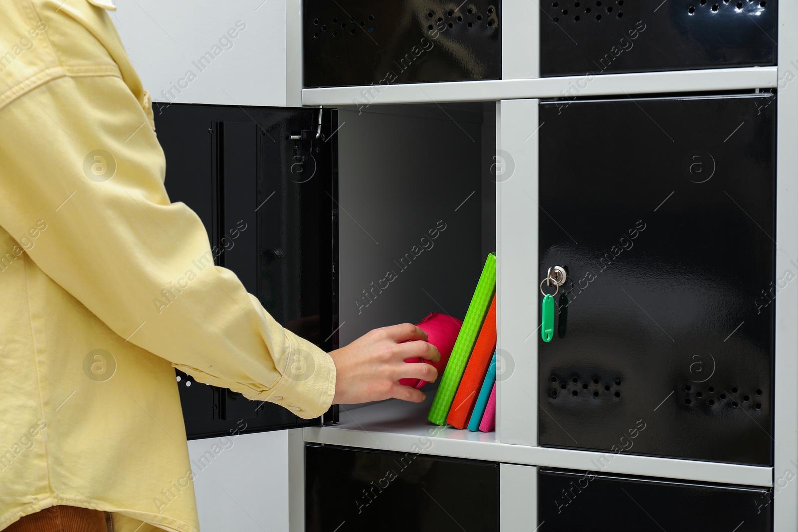 Photo of Woman putting school supplies into locker, closeup