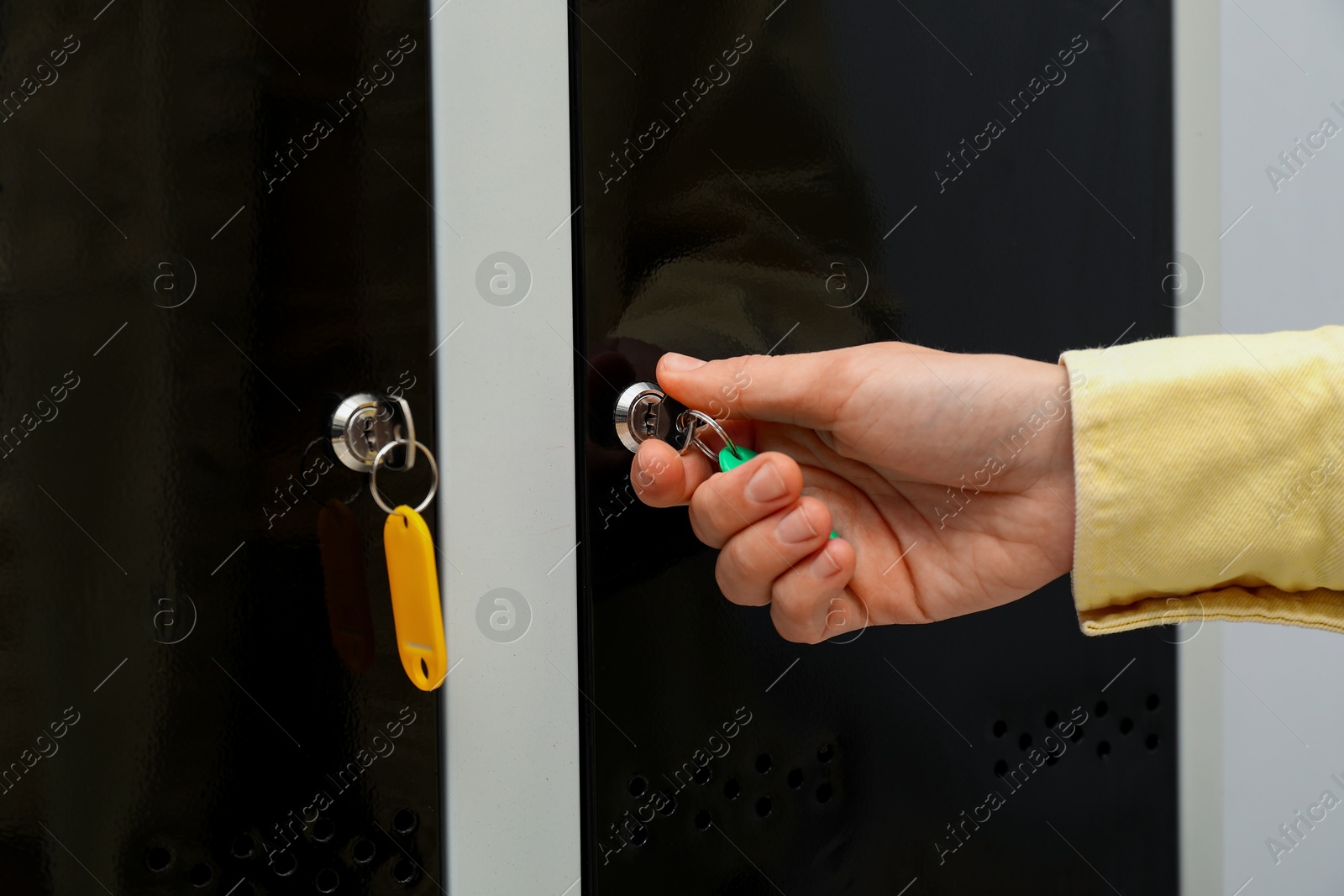 Photo of Woman closing personal locker with key indoors, closeup