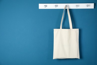 Photo of One eco bag hanging on blue wall. Mockup for design