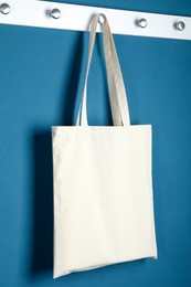 Photo of One eco bag hanging on blue wall. Mockup for design