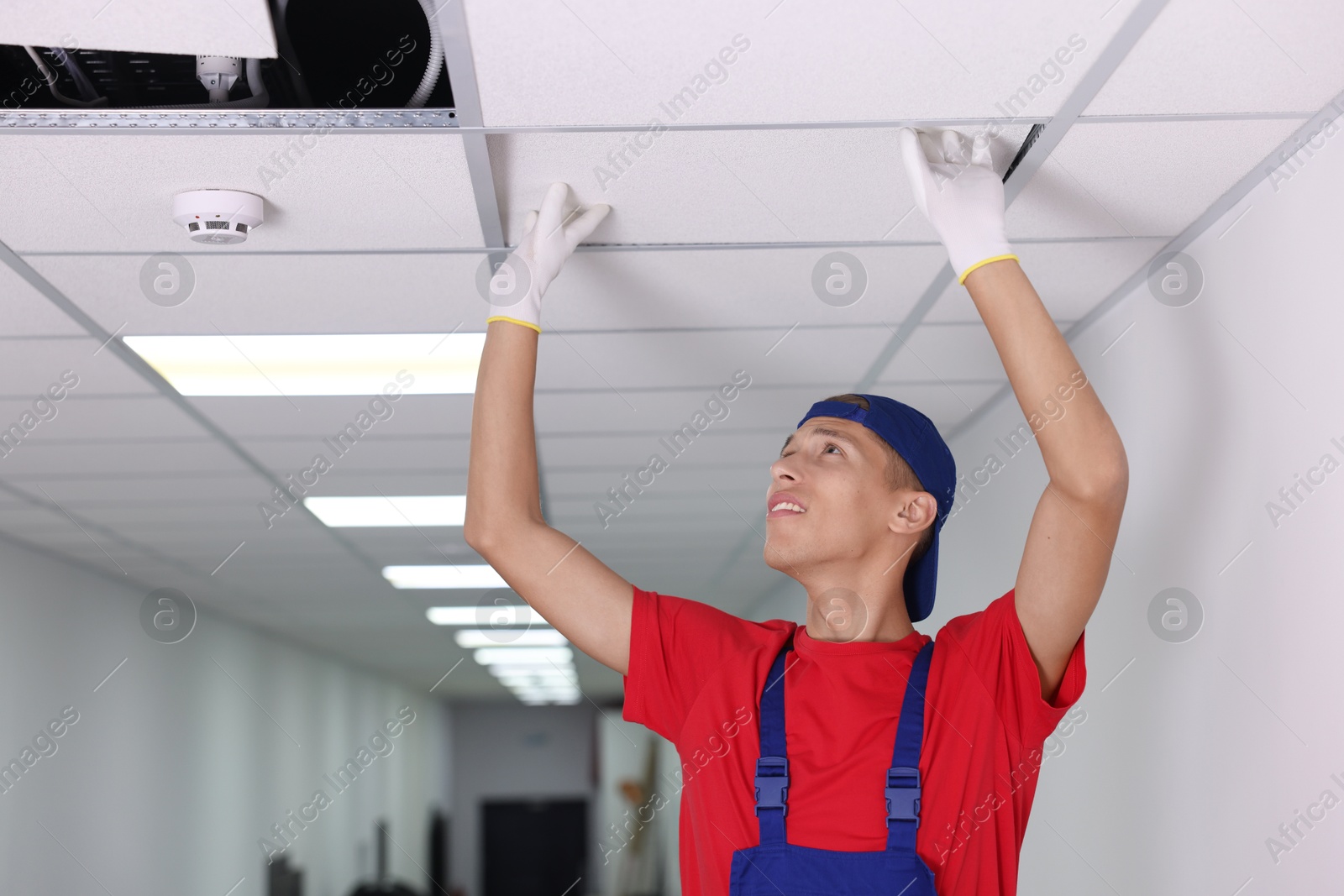 Photo of Suspended ceiling installation. Builder working with PVC tile indoors