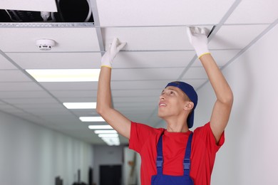 Photo of Suspended ceiling installation. Builder working with PVC tile indoors