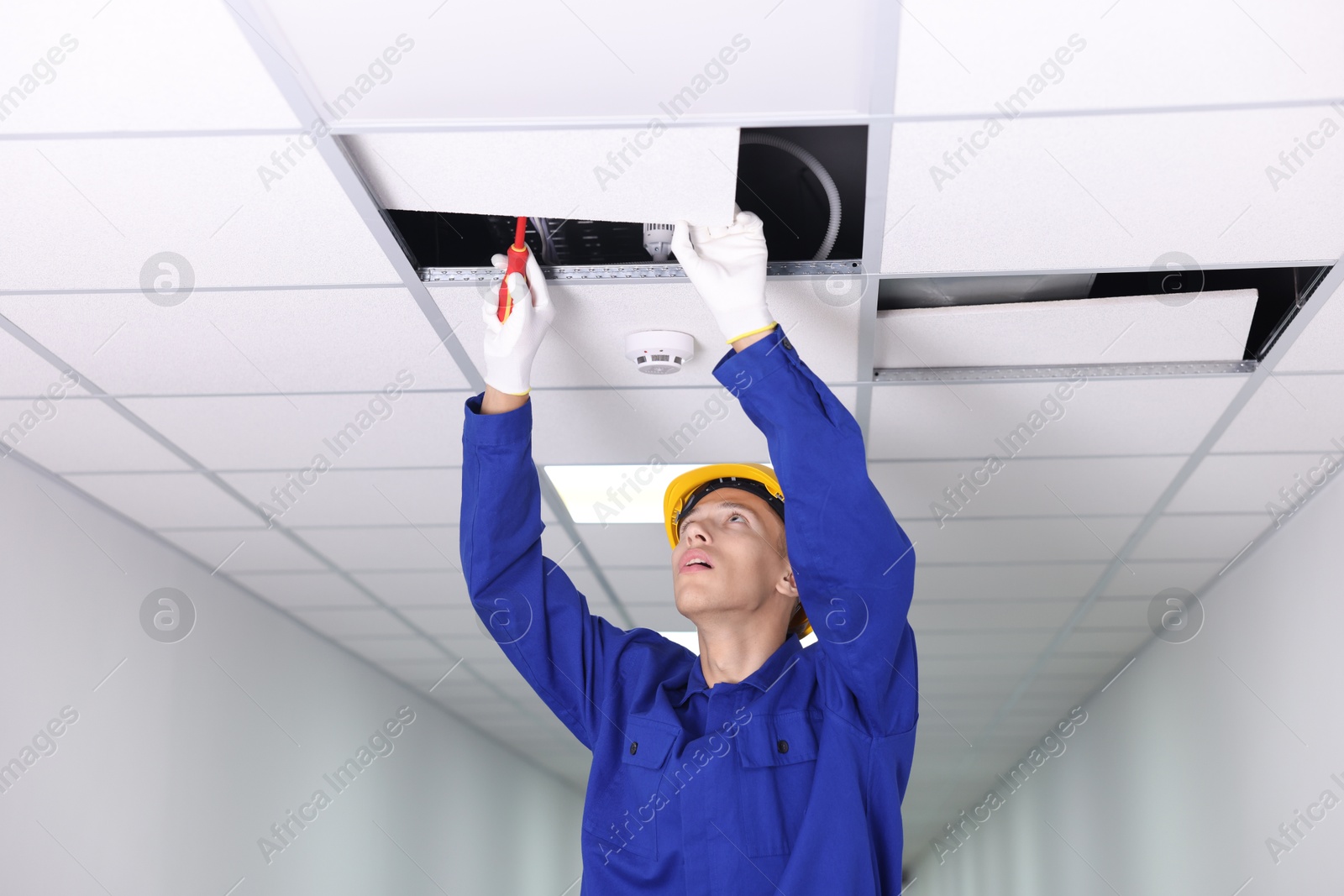 Photo of Suspended ceiling installation. Builder working with PVC tile indoors