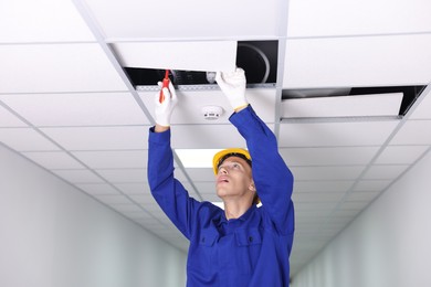 Photo of Suspended ceiling installation. Builder working with PVC tile indoors