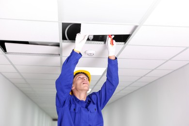 Photo of Suspended ceiling installation. Builder working with PVC tile indoors