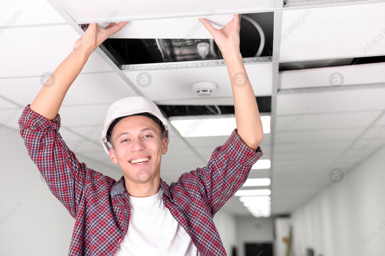 Photo of Suspended ceiling installation. Builder working with PVC tile indoors