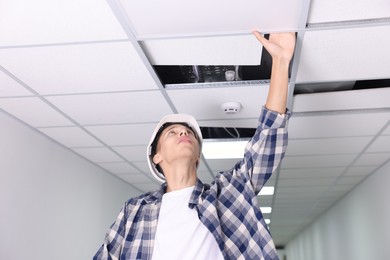 Photo of Suspended ceiling installation. Builder working with PVC tile indoors