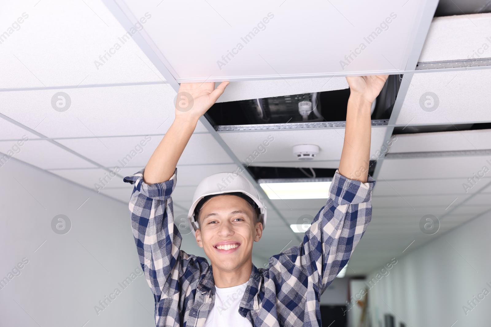 Photo of Suspended ceiling installation. Builder working with PVC tile indoors