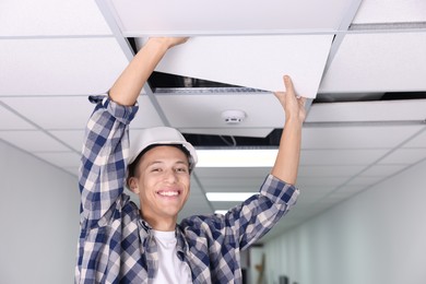 Photo of Suspended ceiling installation. Builder working with PVC tile indoors